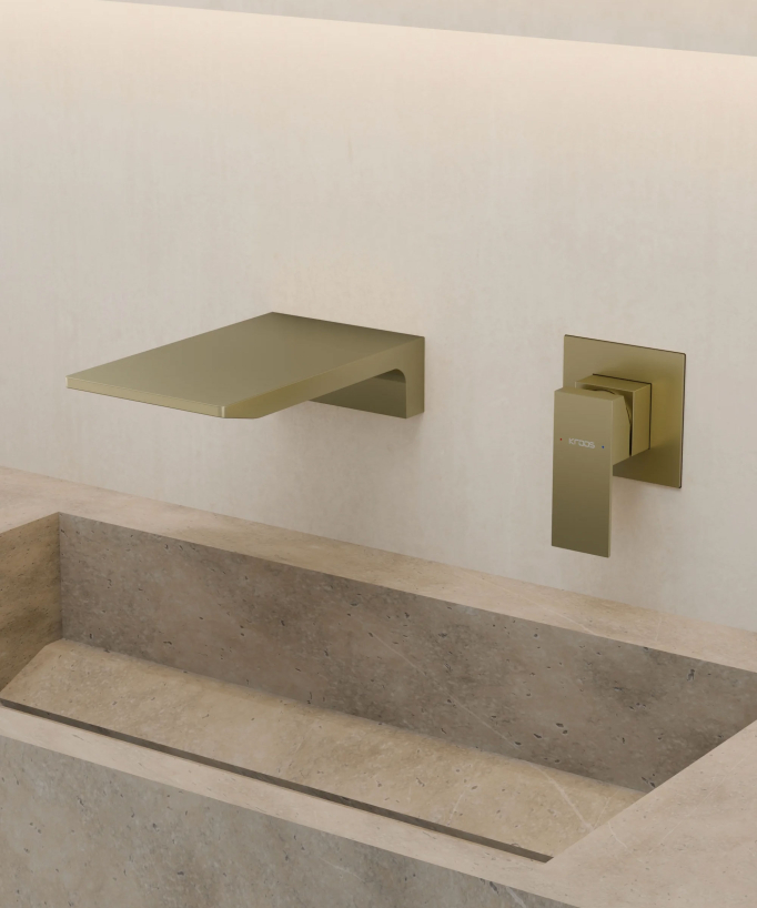 Mitigeur lavabo mural cascade Doré brossé Thilia, posé au-dessus d'une vasque en pierre ton beige